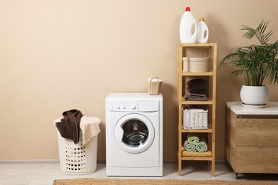 Stylish laundry room interior with washing machine, furniture and houseplant