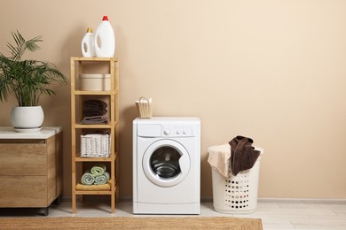 Photo of Stylish laundry room interior with washing machine, furniture and houseplant