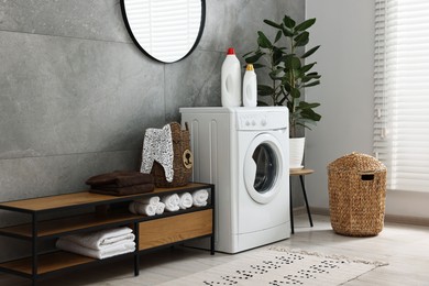 Washing machine, detergents, houseplant, baskets and storage cabinet in laundry room