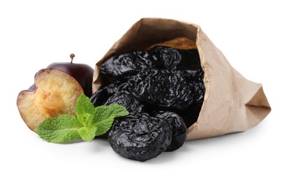 Photo of Paper bag with delicious prunes, fresh ripe plums and mint isolated on white