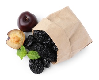 Photo of Paper bag with delicious prunes, fresh ripe plums and mint isolated on white, top view