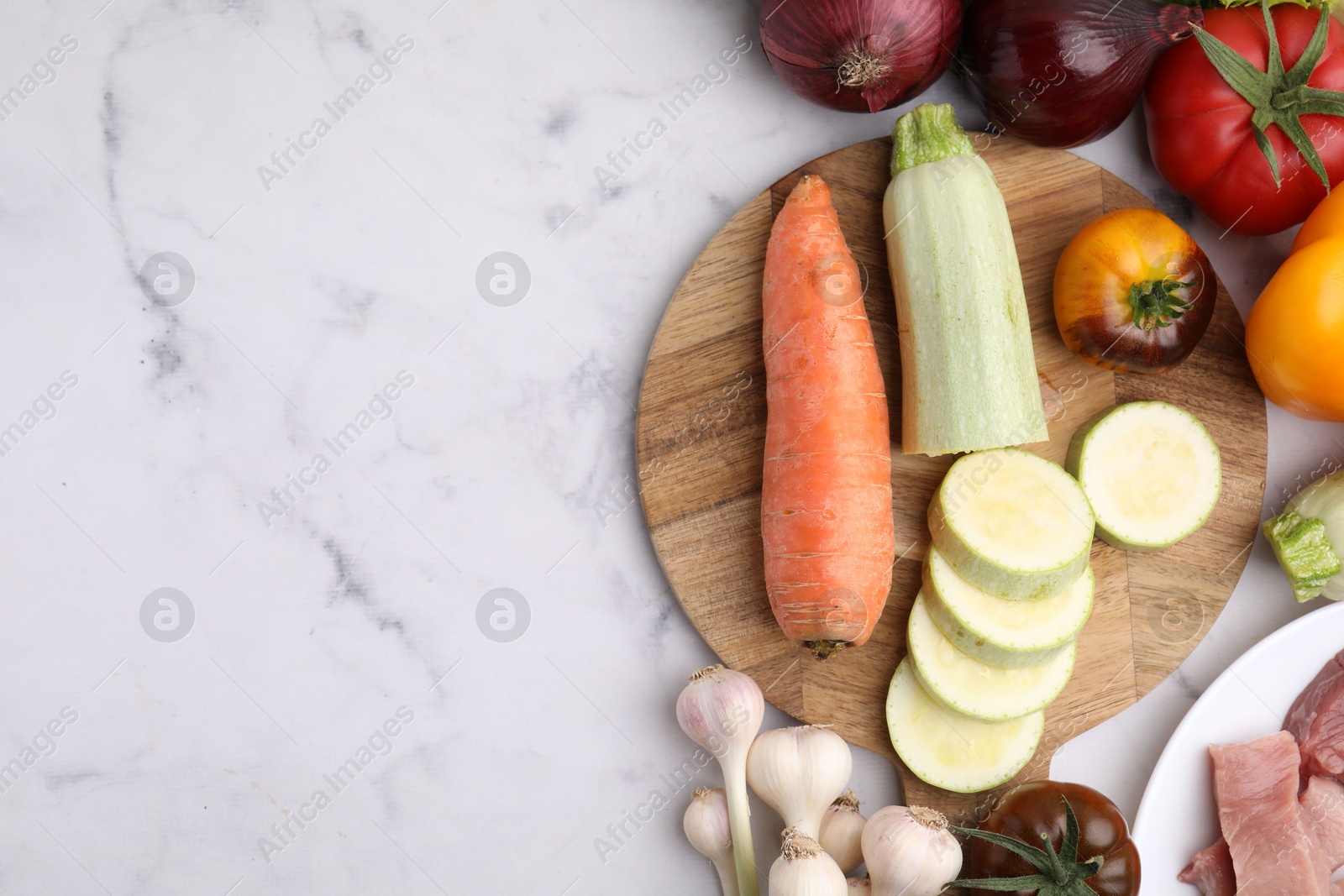 Photo of Different vegetables and raw meat for stew on white marble table, top view. Space for text