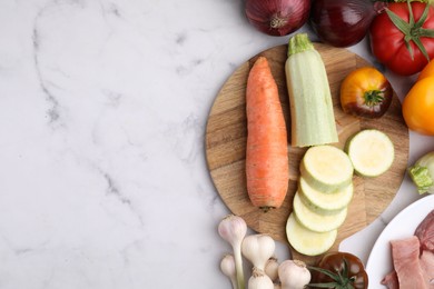 Different vegetables and raw meat for stew on white marble table, top view. Space for text