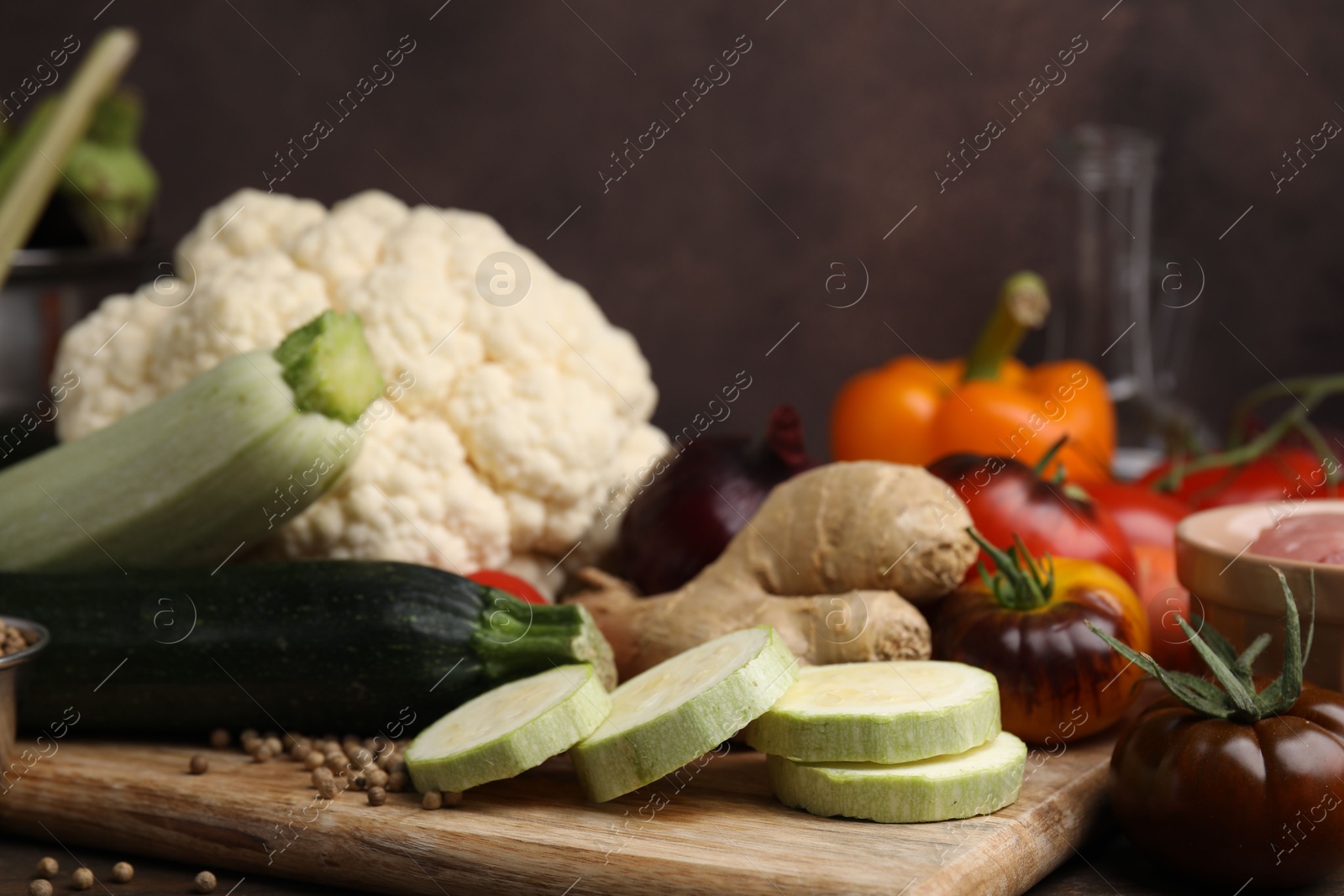 Photo of Cooking tasty stew. Fresh zucchini, ginger, tomatoes, cauliflower and peppercorns on table