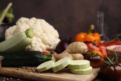 Photo of Cooking tasty stew. Fresh zucchini, ginger, tomatoes, cauliflower and peppercorns on table