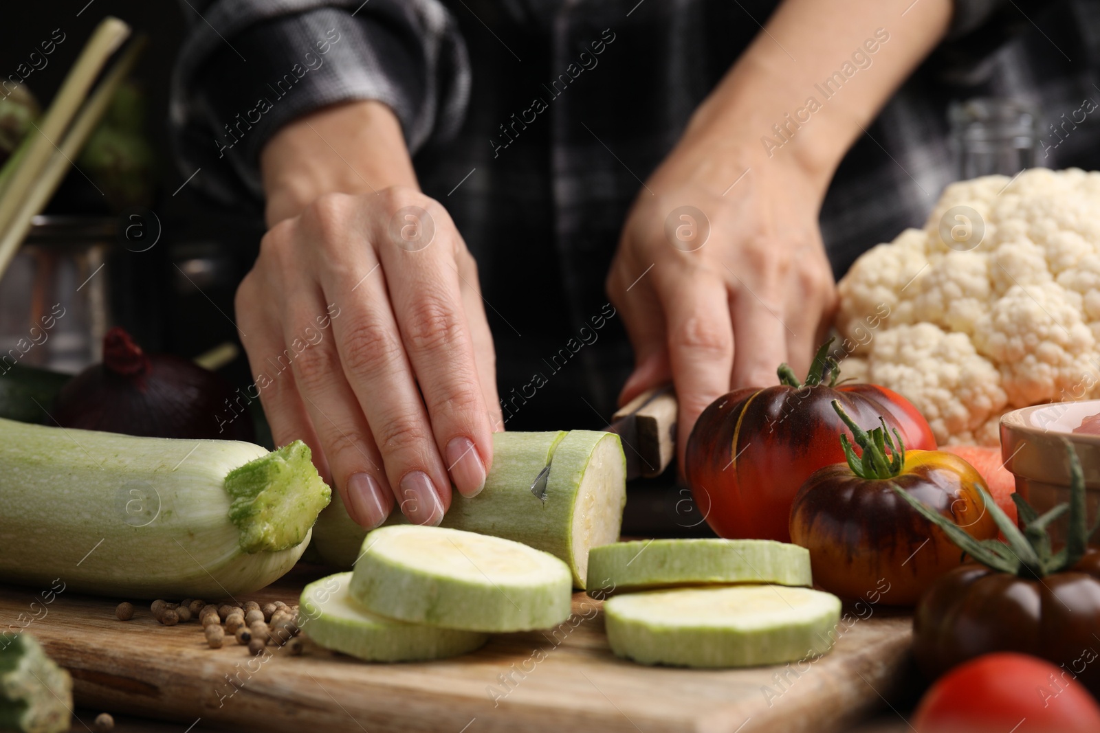 Photo of Cooking vegetable stew. Woman cutting zucchini at table, closeup