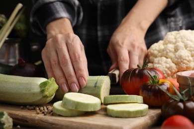 Photo of Cooking vegetable stew. Woman cutting zucchini at table, closeup