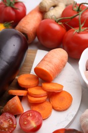 Photo of Cooking tasty stew. Cut carrot, tomatoes and eggplant on table