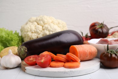 Different vegetables and raw meat for stew on white table