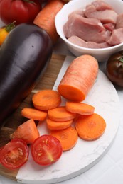 Different vegetables and raw meat for stew on white table