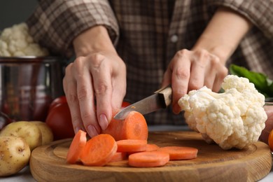 Cooking vegetable stew. Woman cutting carrot at table, closeup