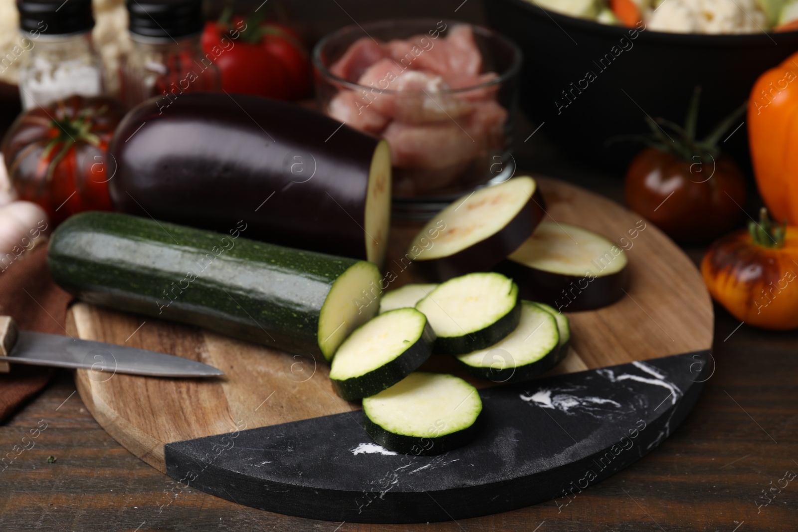 Photo of Cooking stew. Cut zucchini and eggplant on wooden table, closeup