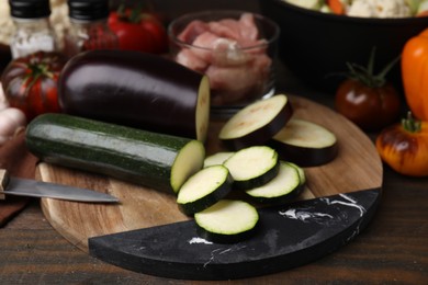 Photo of Cooking stew. Cut zucchini and eggplant on wooden table, closeup