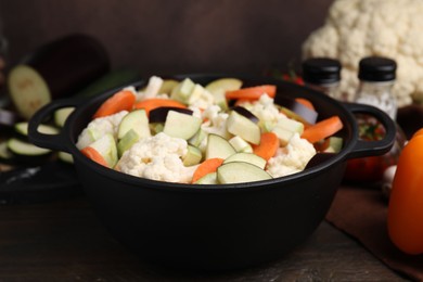 Cooking stew. Cut raw vegetables in pot on wooden table, closeup