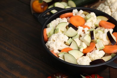 Cooking stew. Cut raw vegetables in pot on wooden table, closeup. Space for text