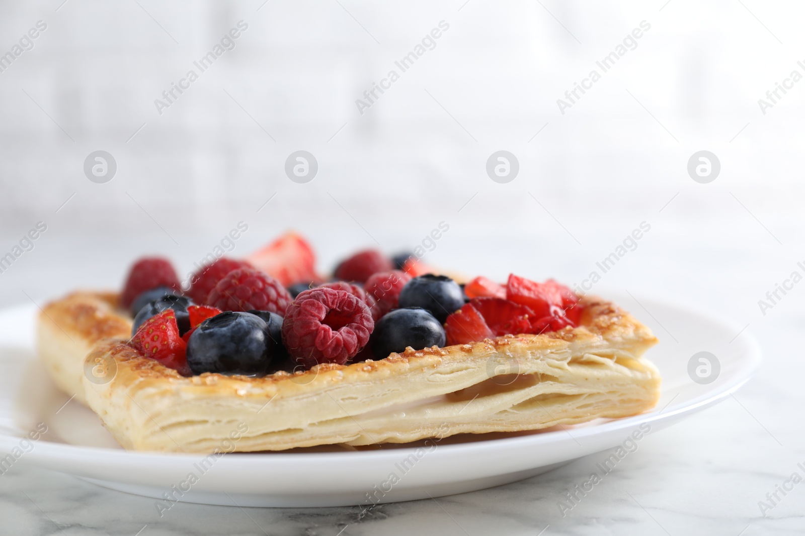 Photo of Tasty puff pastry with berries on white marble table, closeup