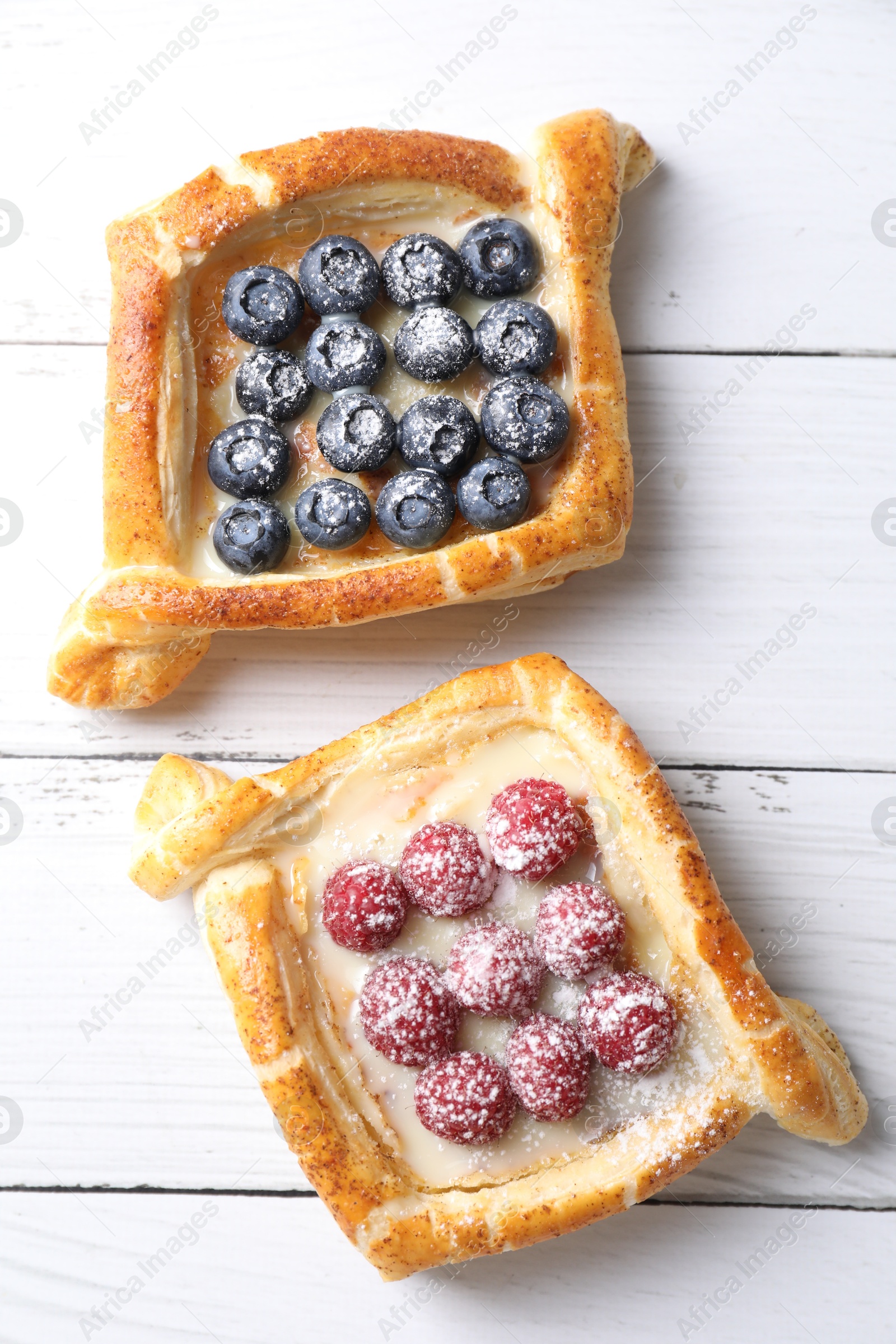 Photo of Tasty puff pastries with berries on white wooden table, top view