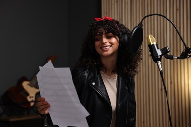 Photo of Singer wearing headphones recording song in professional studio