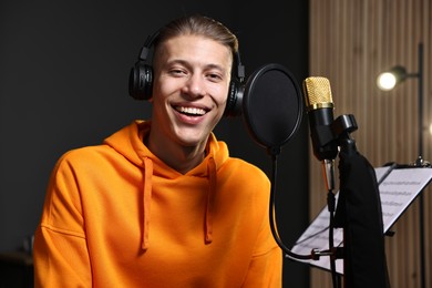 Photo of Singer with headphones recording song in professional studio