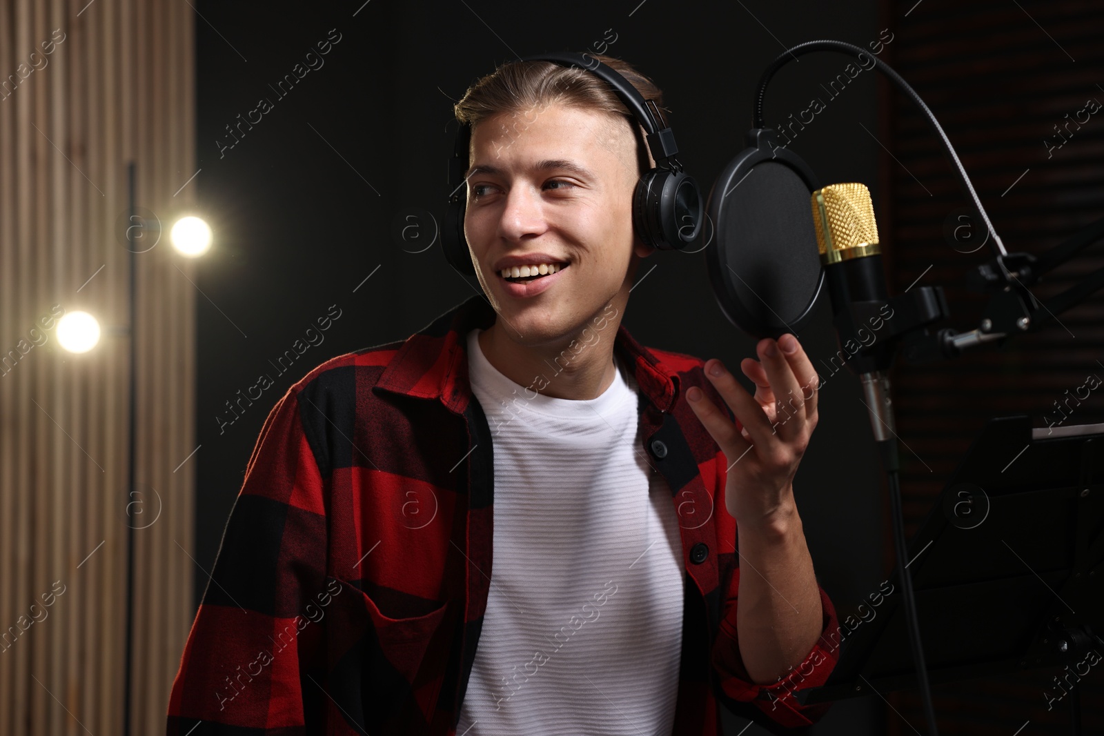 Photo of Singer with headphones recording song in professional studio