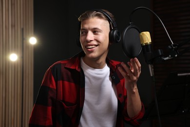 Photo of Singer with headphones recording song in professional studio