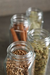 Different spices in glass jars on blurred background, closeup