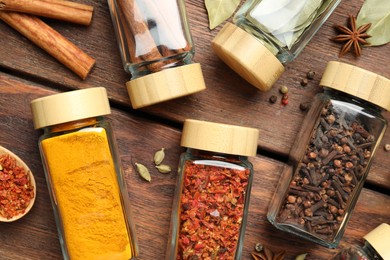 Photo of Different spices in glass jars on wooden table, flat lay