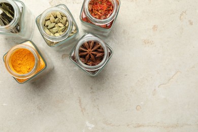 Photo of Different spices in glass jars on light grey table, flat lay. Space for text