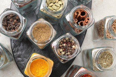 Photo of Different spices in glass jars on light grey table, top view