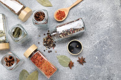 Photo of Different spices in glass jars on grey table, flat lay