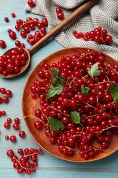 Photo of Fresh red currants and leaves on light blue wooden table, flat lay