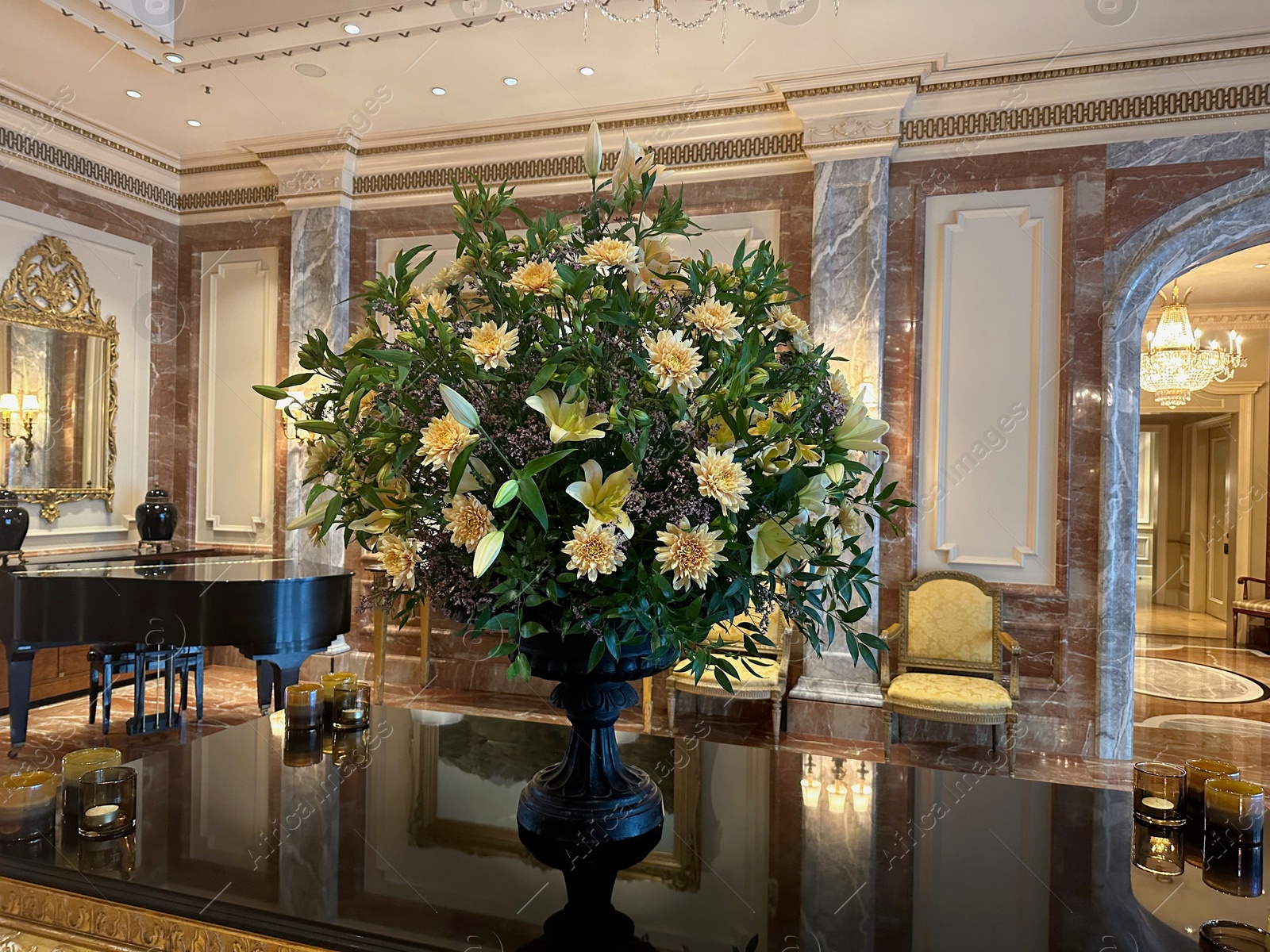 Photo of Vase with beautiful lilies and dahlias on mirrored table in hall of luxury hotel