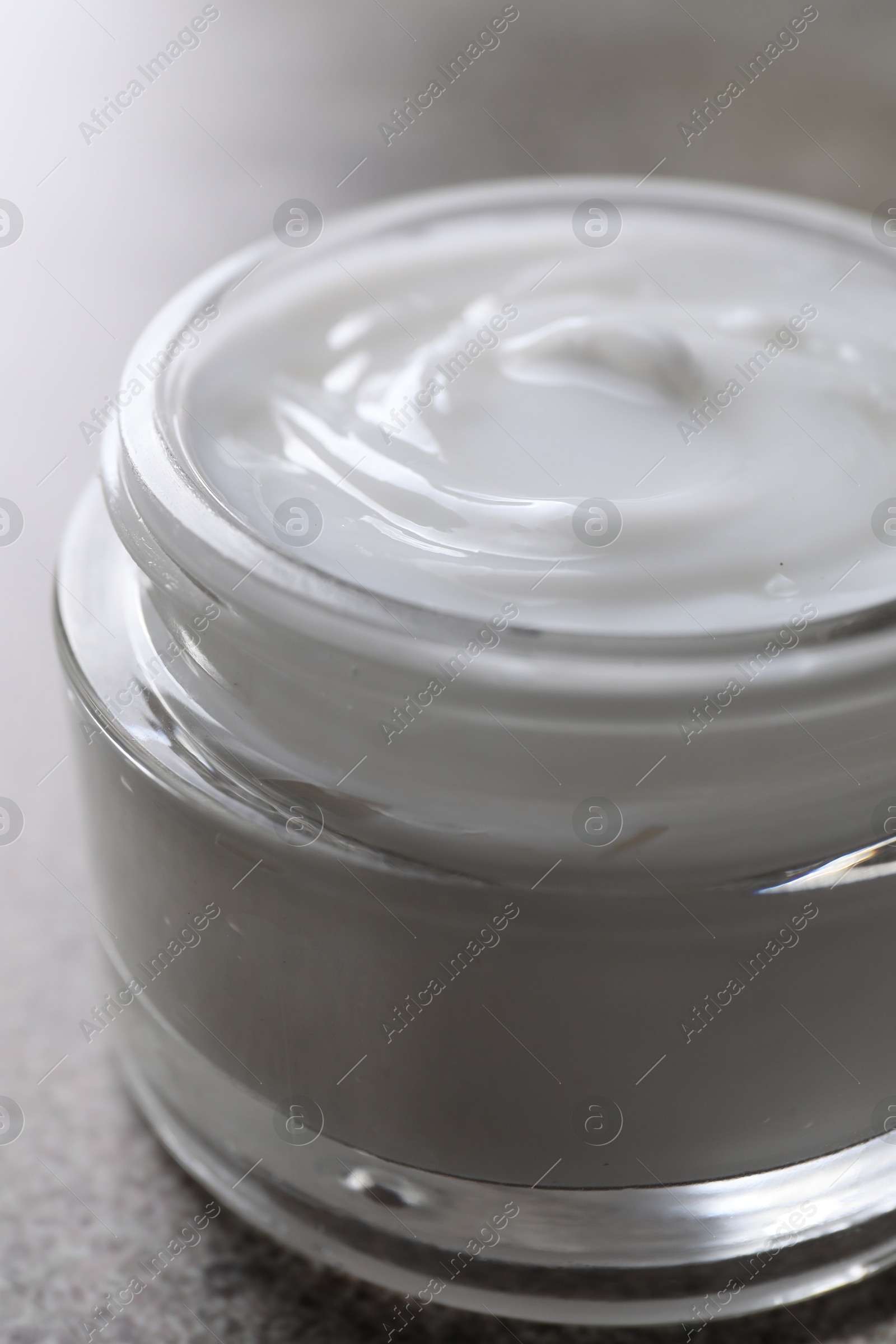 Photo of Face cream in jar on grey table, closeup