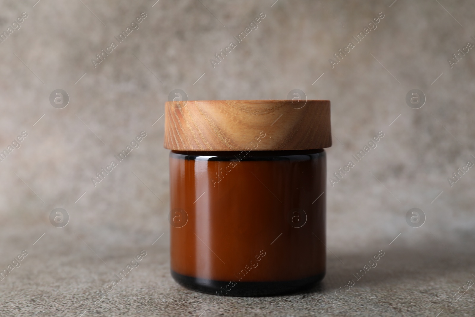 Photo of Face cream in jar on grey textured table, closeup