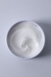 Face cream in jar on white textured table, top view