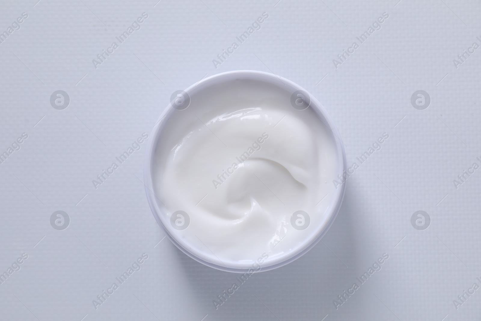 Photo of Face cream in jar on white textured table, top view