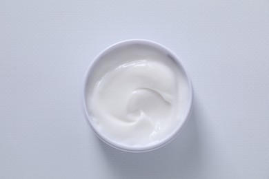 Face cream in jar on white textured table, top view