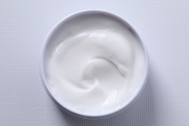 Face cream in jar on white textured table, top view