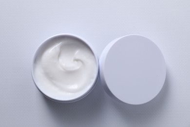 Face cream in jar on white textured table, top view