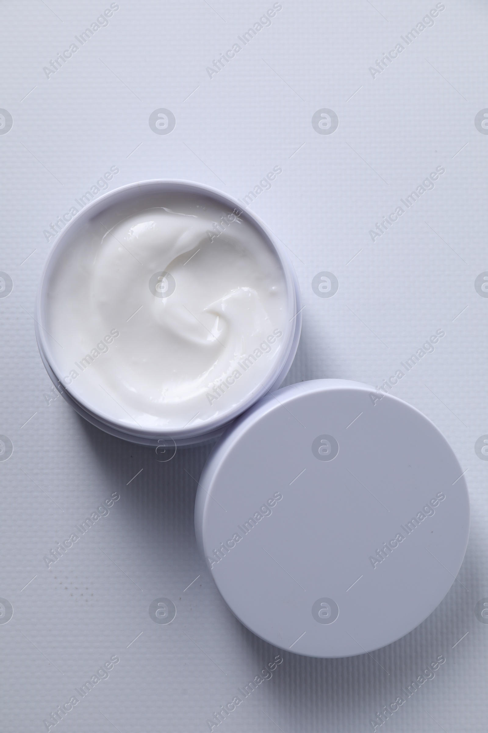 Photo of Face cream in jar on white textured table, top view