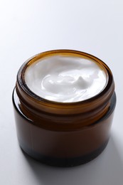 Face cream in jar on white background, closeup