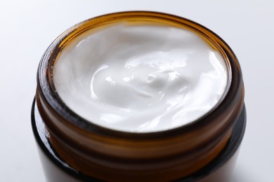 Face cream in jar on white background, closeup