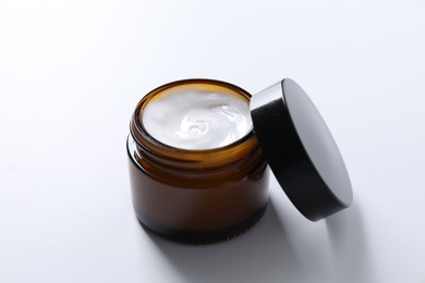 Face cream in jar on white background, closeup