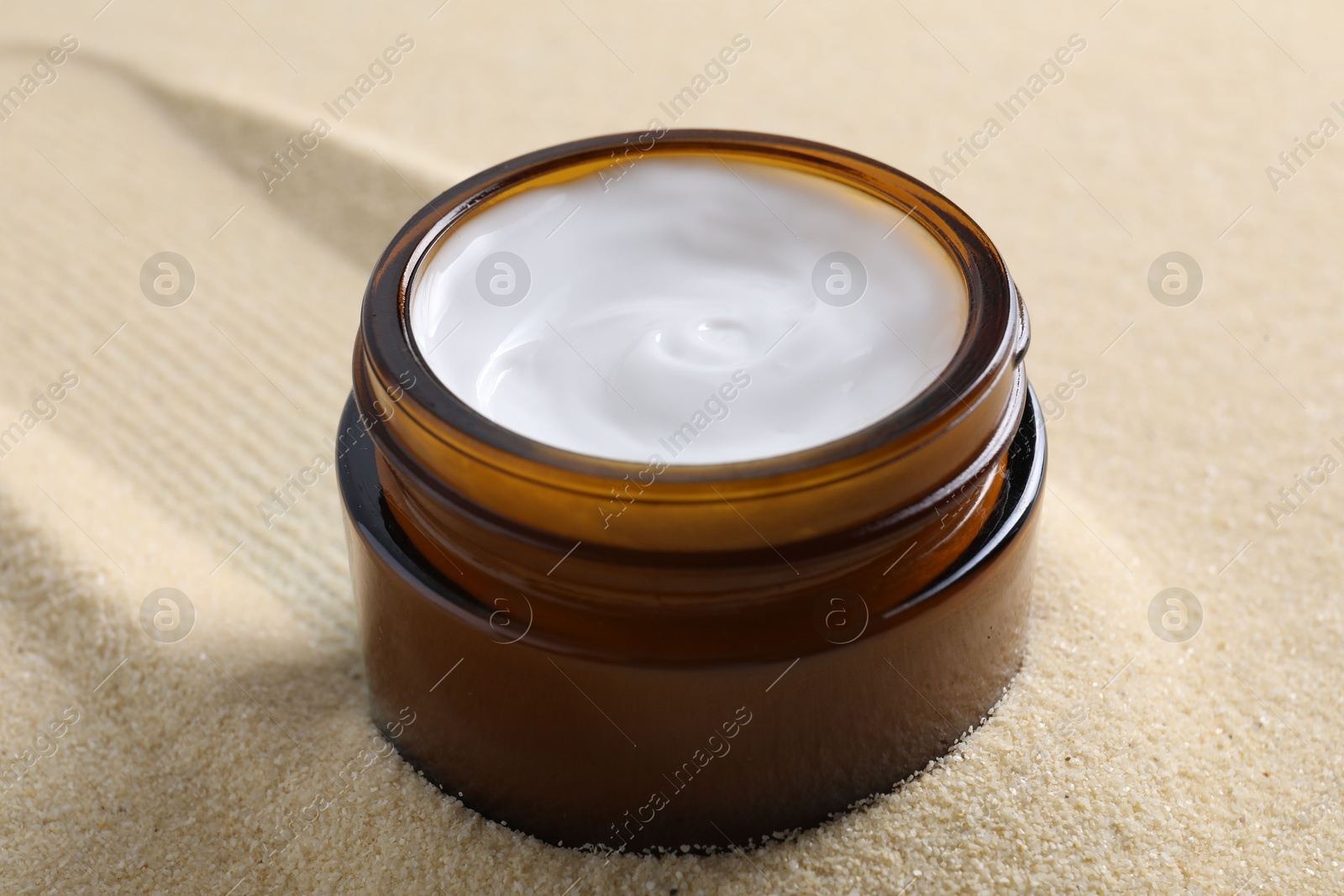 Photo of Face cream in jar on beige textured background, closeup