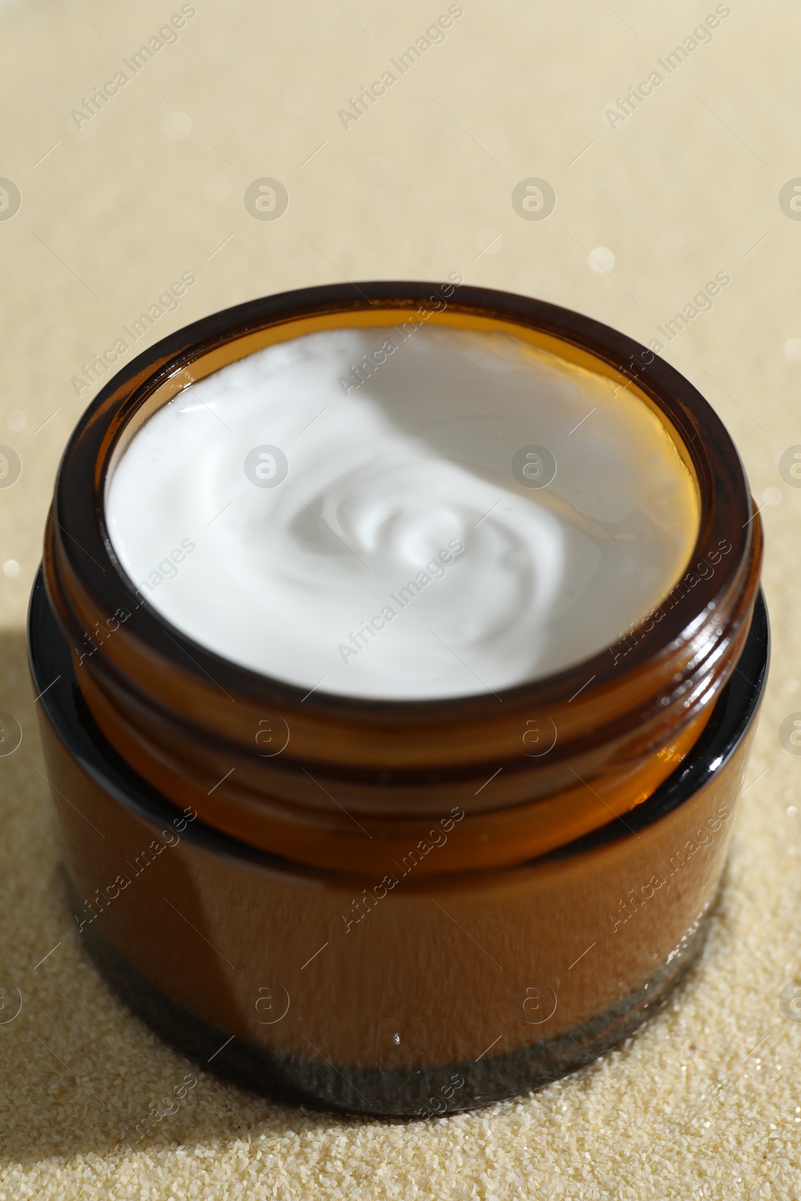 Photo of Face cream in jar on beige textured background, closeup