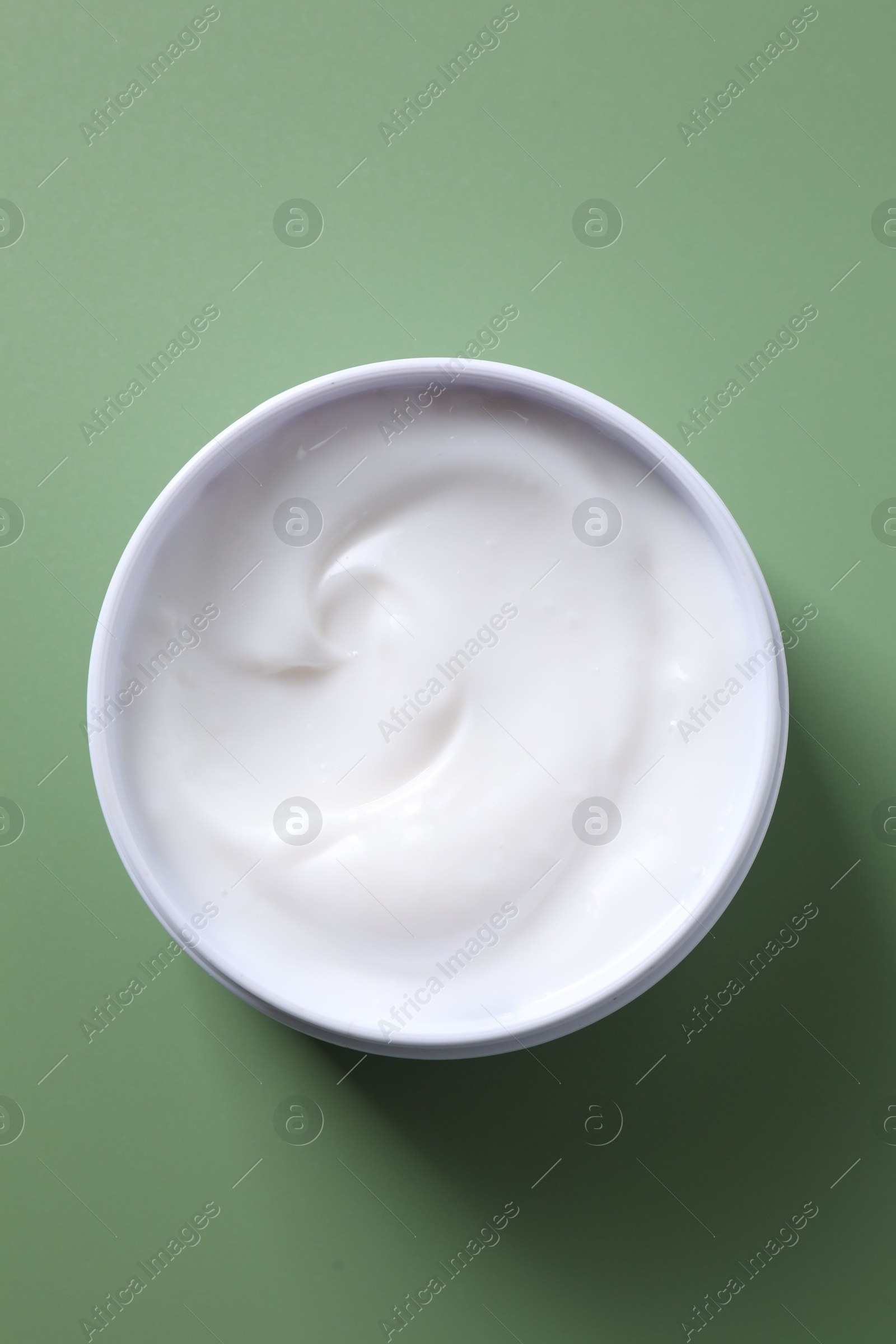 Photo of Face cream in jar on green background, top view