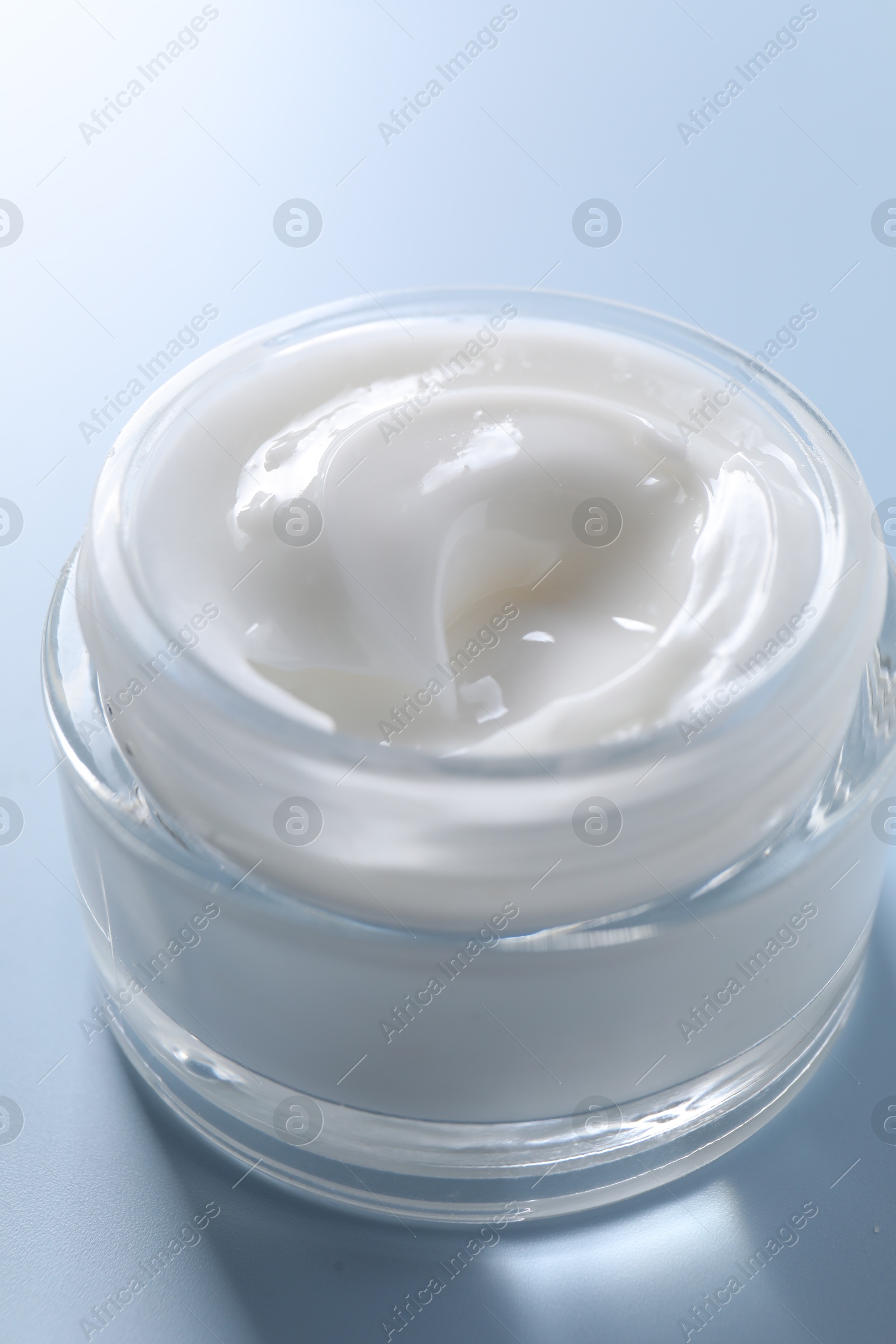 Photo of Face cream in jar on light blue background, closeup