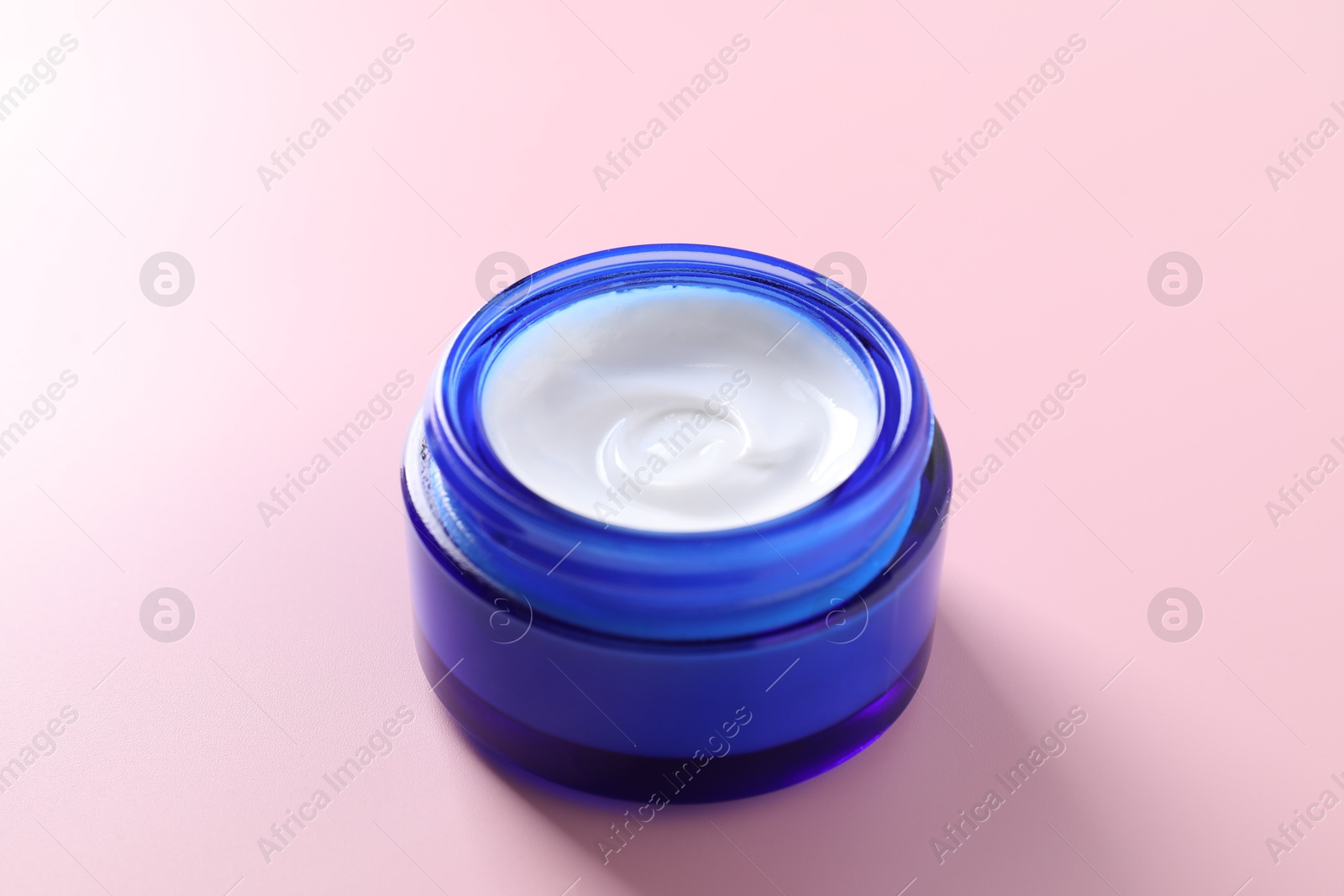 Photo of Face cream in jar on pink background, closeup