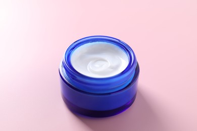 Face cream in jar on pink background, closeup