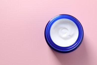 Face cream in jar on pink background, top view. Space for text